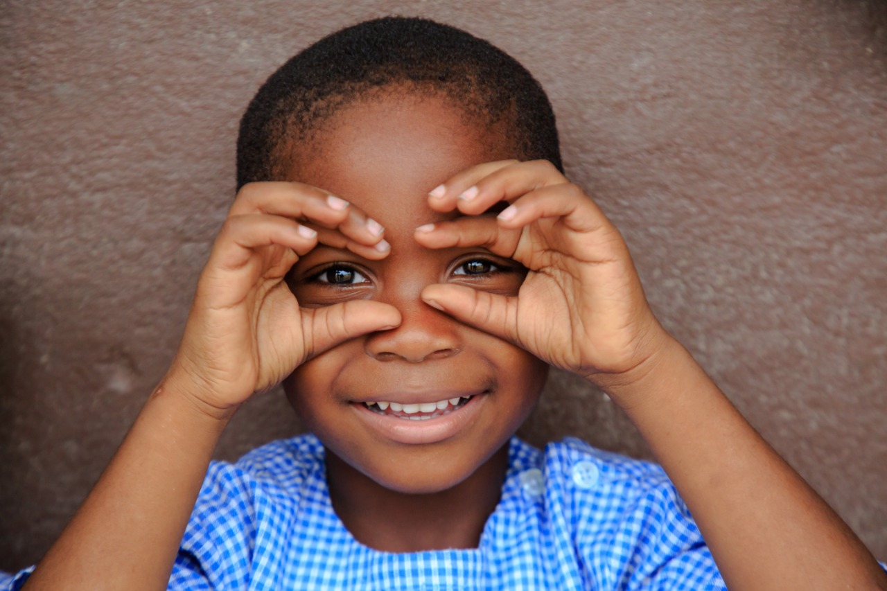 Niño sonriendo y haciendo un gesto de gafas UNICEF
