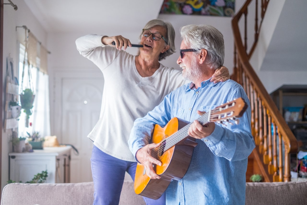 Un par de adultos mayores cantando y bailando juntos en cohousing.