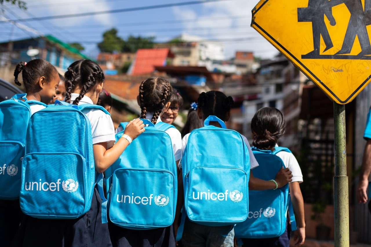 niños y niñas en la calle con sus maletas de UNICEF 