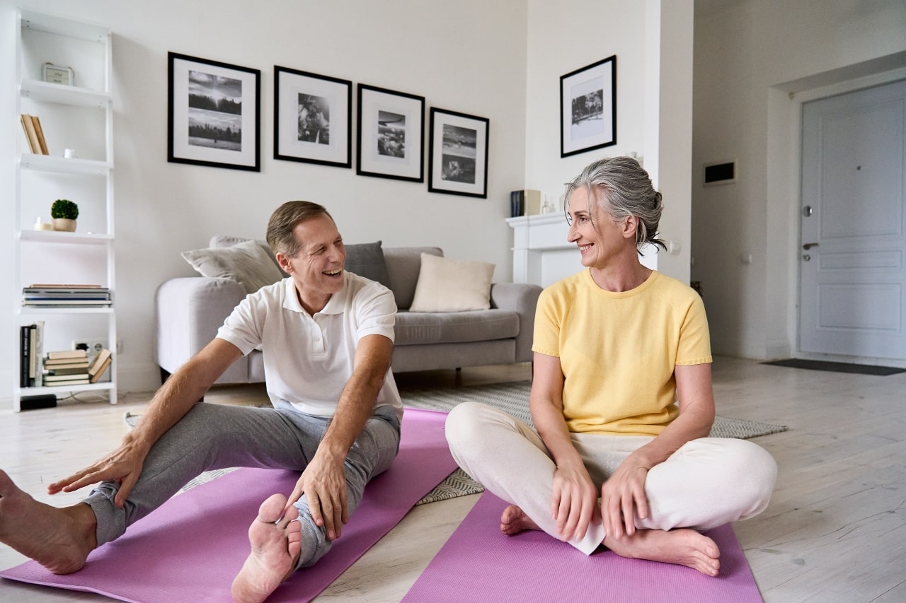 pareja de adultos con energía positiva haciendo ejercicios de estiramiento en casa.