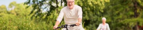 hombre de 60 años feliz en bicicleta dando un paseo rodeado de naturaleza