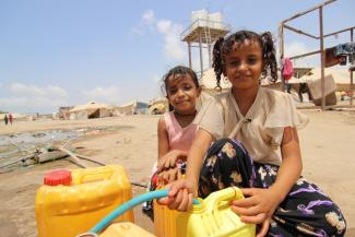 Dos niñas llenando recipientes en un punto de agua potable UNICEF Colombia