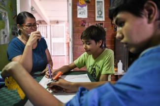 niños dibujando en compañía de una mujer-Unicef Colombia
