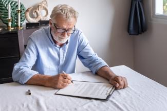 Señor de tercera edad leyendo y firmando su testamento
