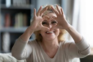 Mujer feliz sentada en la sala haciendo con sus manos la forma de un corazón