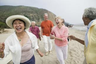 Amigos mayores de edad corriendo en la playa mientras ríen y disfrutan la vida Amigos mayores de edad corriendo en la playa mientras ríen y disfrutan la vida