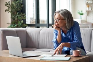 Señora haciendo cursos online para adultos mayores en la sala de su casa con un cuaderno y un café Señora haciendo cursos online para adultos mayores en la sala de su casa con un cuaderno y un café