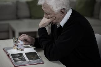 Un hombre de la tercera edad revisa detenidamente un álbum de fotos. 