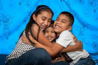 Niños y niñas se abrazan entre ellos mientras sonríen  