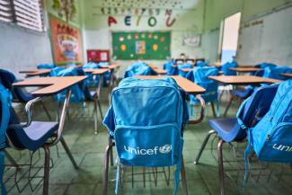 Un aula de clases llena de pupitres que portan las maletas de UNICEF Colombia. 